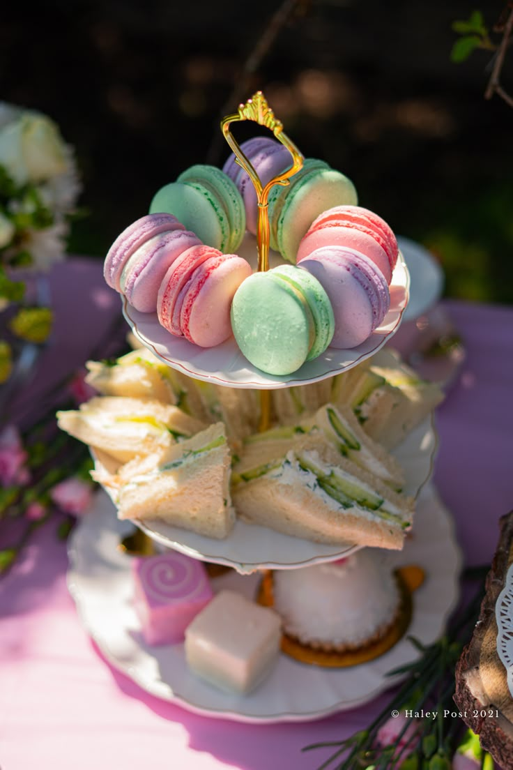 three tiered trays filled with pastries on top of a purple table cloth