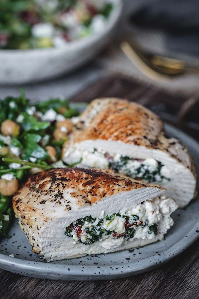 chicken breast with spinach and chickpeas on a plate next to a salad