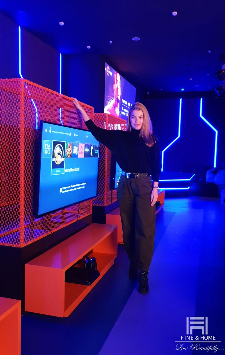 a woman standing in front of a flat screen tv with blue lights on it's sides