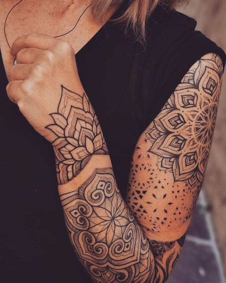 a woman's arm with tattoos on it and an intricate design in the middle