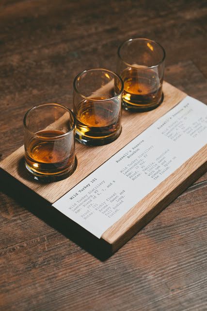 three shot glasses sitting on top of a wooden tray