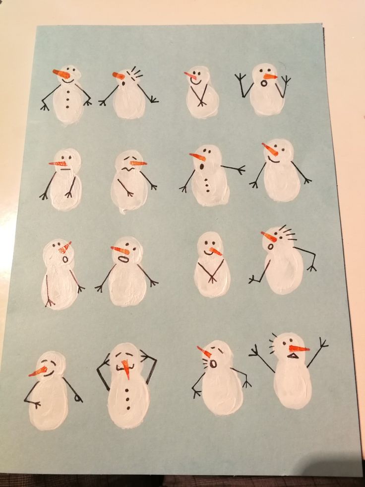 the snowmen are drawn on paper and placed in front of a white tablecloth