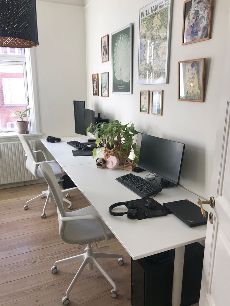 a desk with several computers and plants on it