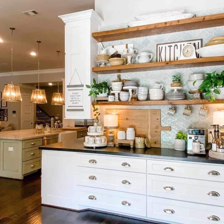 a kitchen filled with lots of white cabinets and counter top covered in pots and pans