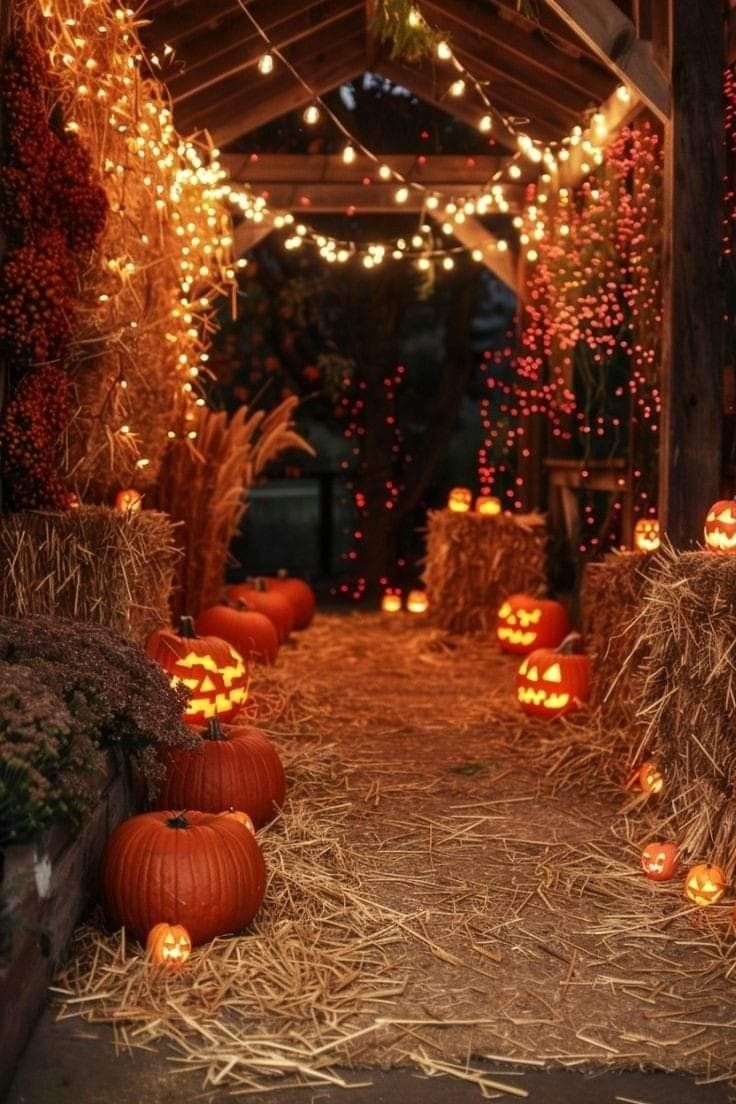 pumpkins and hay bales are lit up in an outdoor area with lights strung from the ceiling