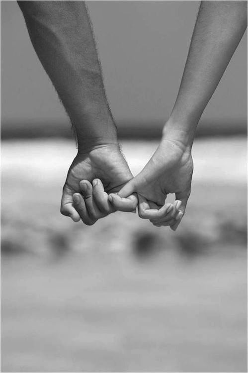 two people holding hands while standing on the beach