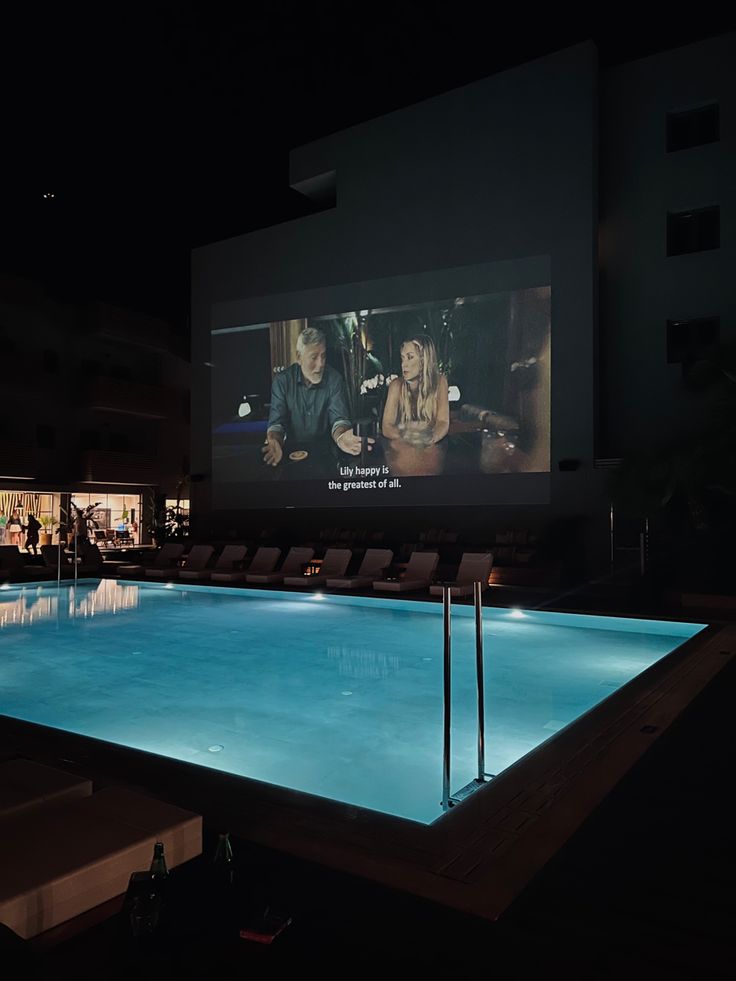 an outdoor movie screen next to a swimming pool