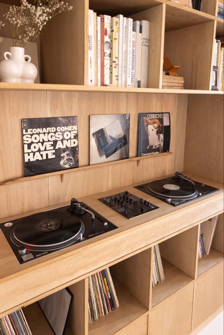 two turntables are sitting in front of bookshelves with records on them