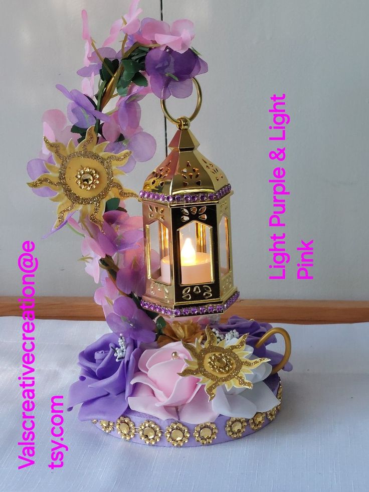 a decorative lantern with flowers on it sitting on a white tablecloth covered table cloth