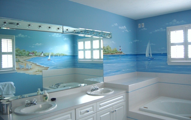 a bathroom with blue and white wallpaper has a large mirror over the bathtub