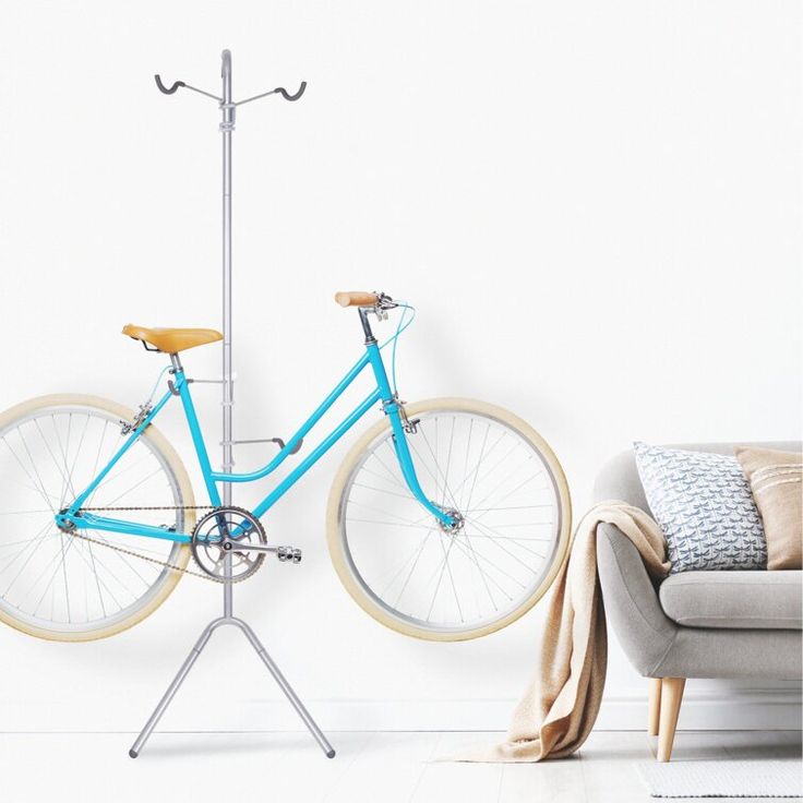 a blue bicycle mounted to the side of a white wall next to a gray couch