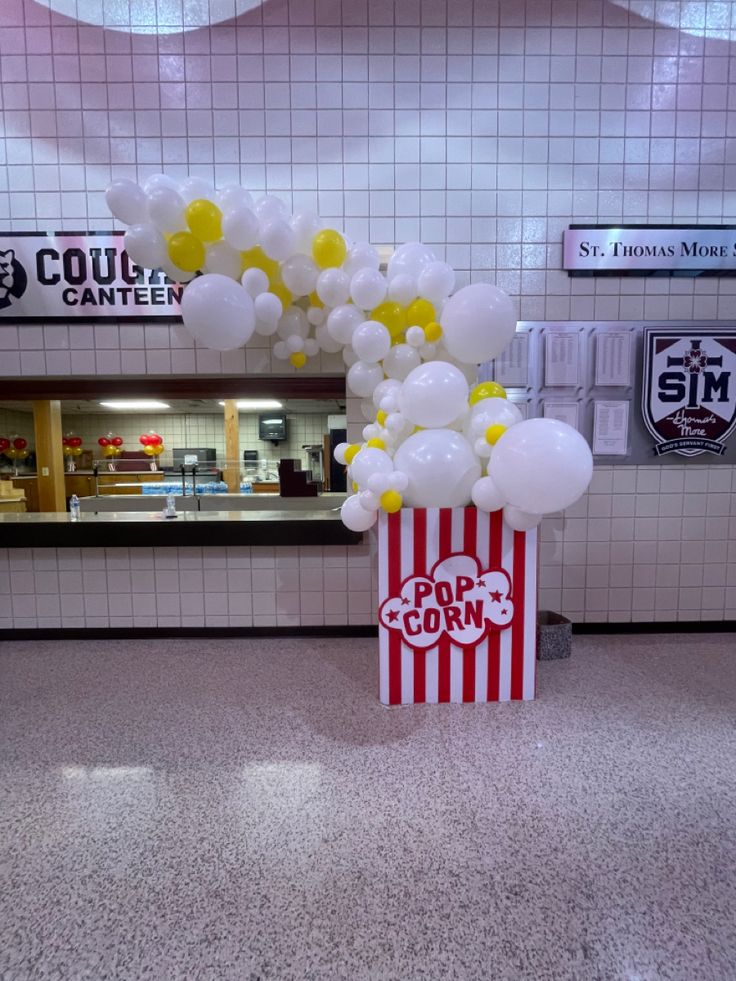 a popcorn box filled with balloons sitting on top of a floor next to a counter