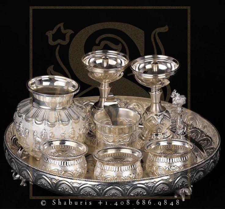 an ornate silver tray with three candles and four cups on it, all in the same pattern