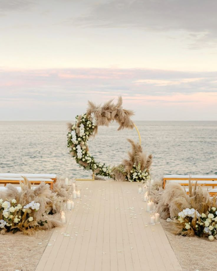 an outdoor ceremony setup with pamolite and white flowers on the aisle leading to the ocean