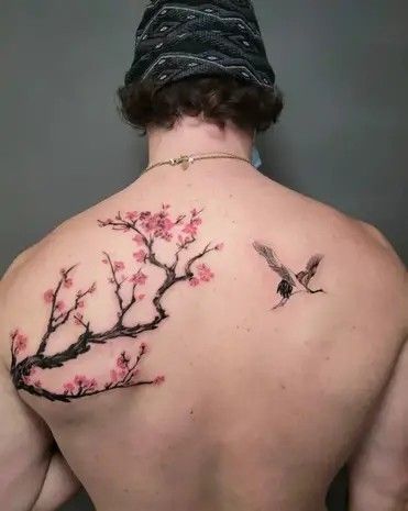 the back of a man with tattoos on his upper and lower back, which is covered in pink flowers