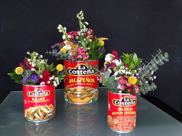 three tins with flowers in them sitting on a table