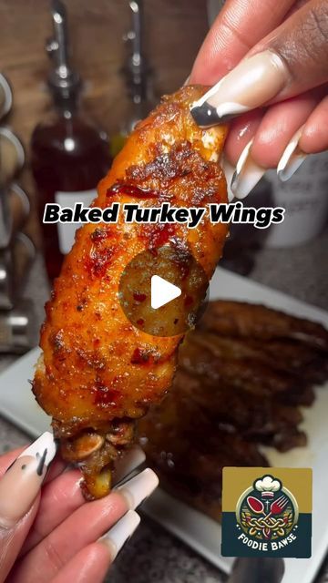 a person holding a piece of food in their hand with the words baked turkey wings on it