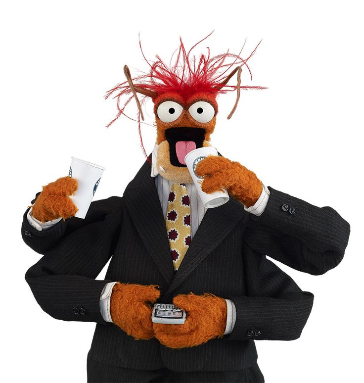 the puppet is dressed in a suit and tie with red hair, holding a cup