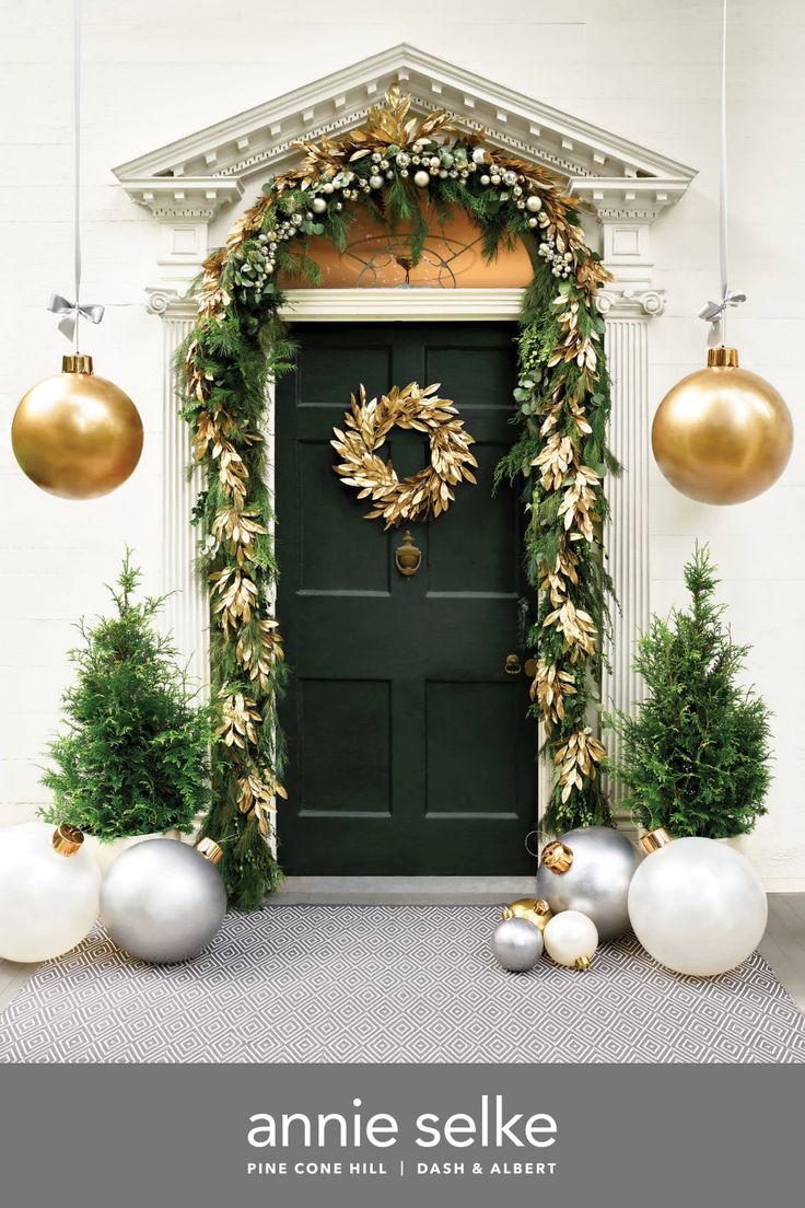 an entrance decorated for christmas with ornaments and greenery on the front door, surrounded by white balls