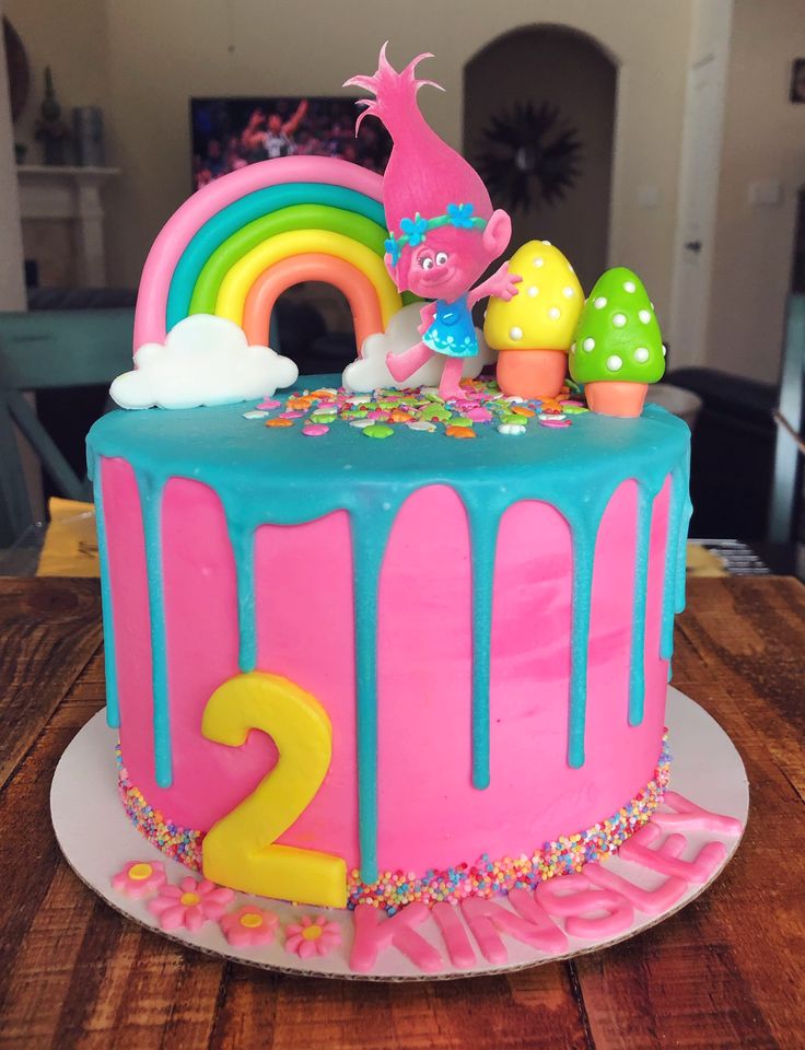 a birthday cake with the number two on it and an image of a rainbow in the background