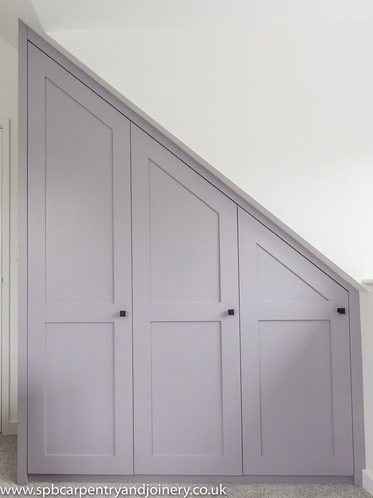 an attic bedroom with gray painted closets and carpeted flooring, along with white walls