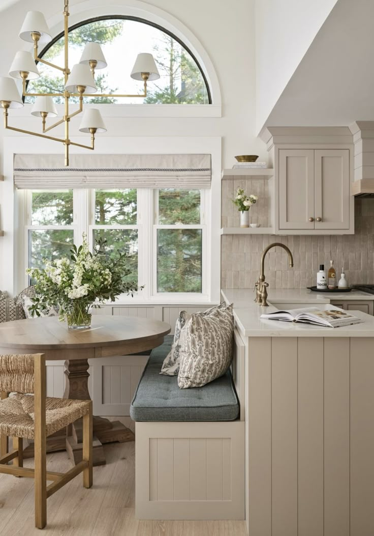 a kitchen with a table, chairs and window in the center is decorated with white flowers