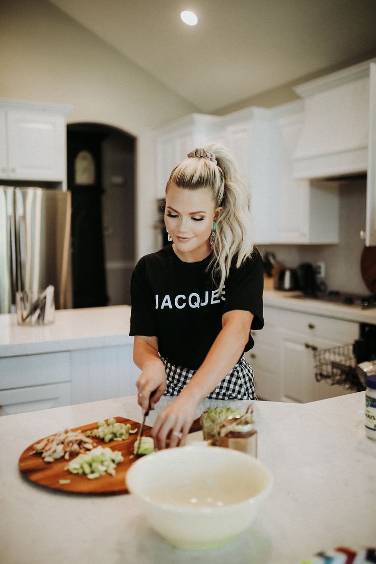 a woman cutting up food on top of a kitchen counter