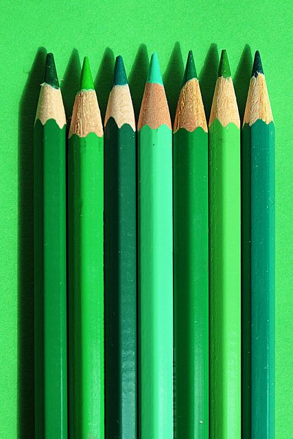 six green pencils lined up in a row on a green surface with the top one turned upside down