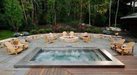 an outdoor hot tub surrounded by chairs and fire pit in the middle of a wooden deck