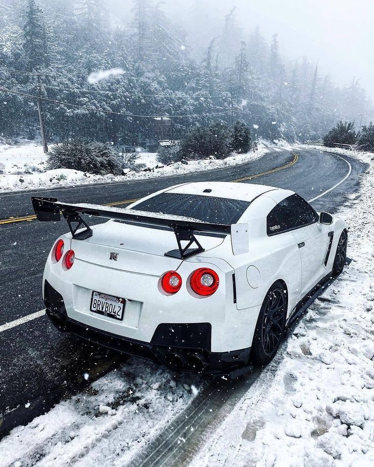 a white sports car driving down a snowy road