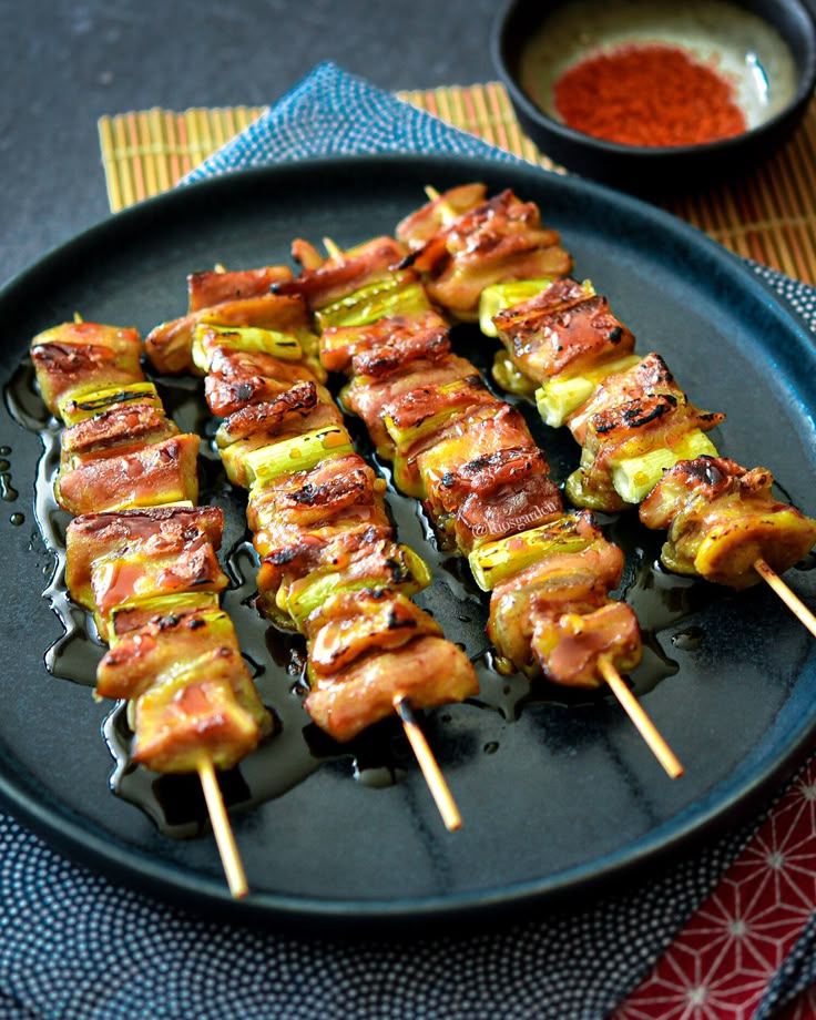 several skewers of food on a black plate