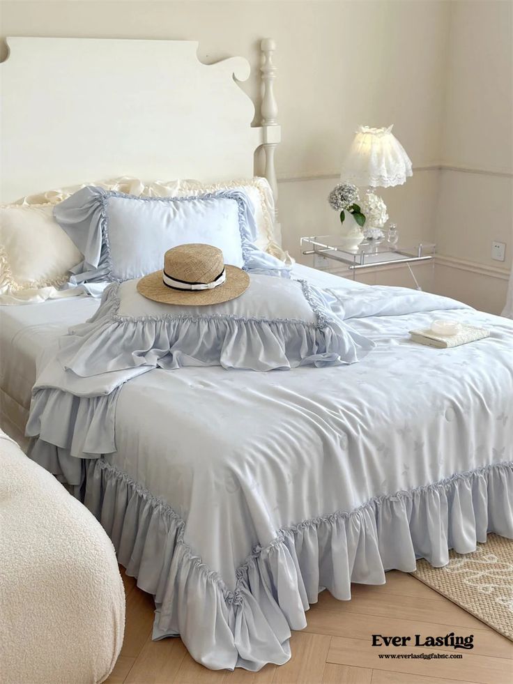 a bed with blue ruffled bedspread and hat on it's headboard