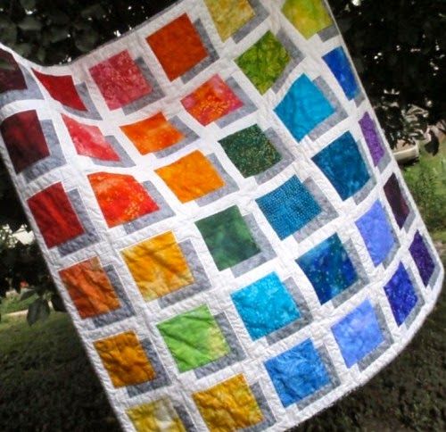 a multicolored quilt hanging from a tree