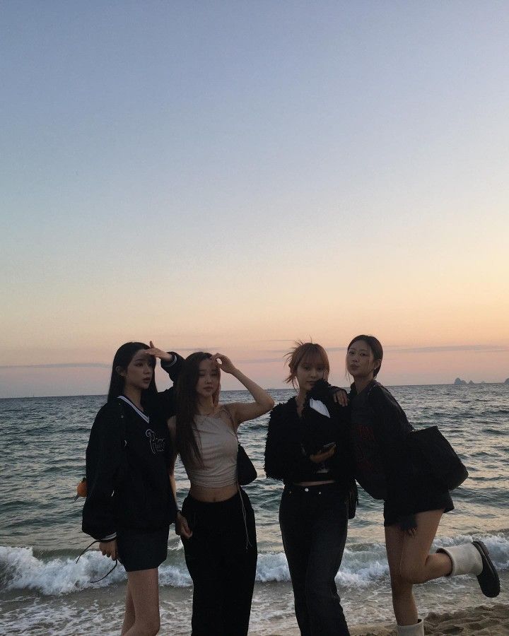 four young women are standing on the beach