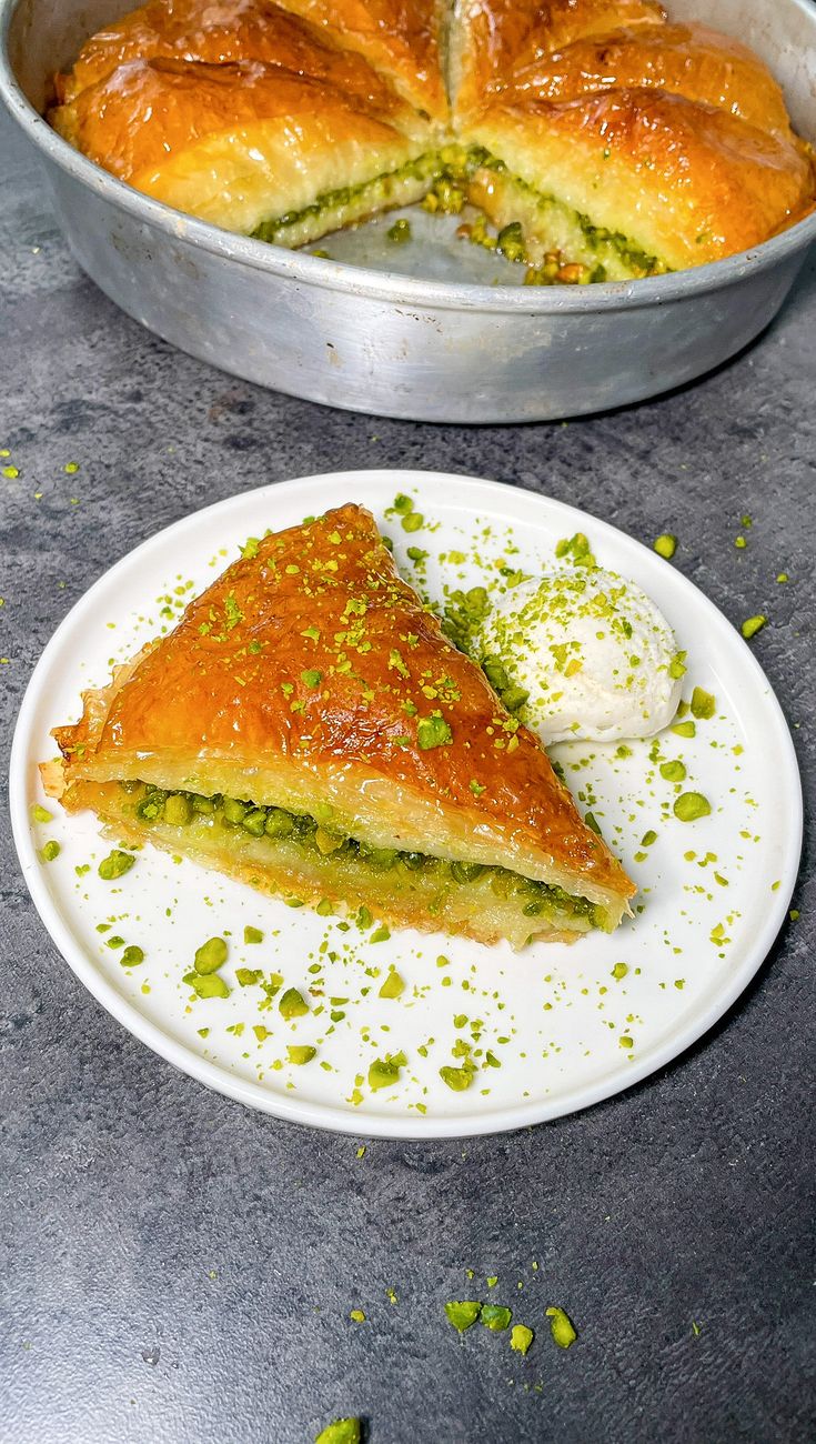 a piece of pie sitting on top of a white plate next to a pan filled with food