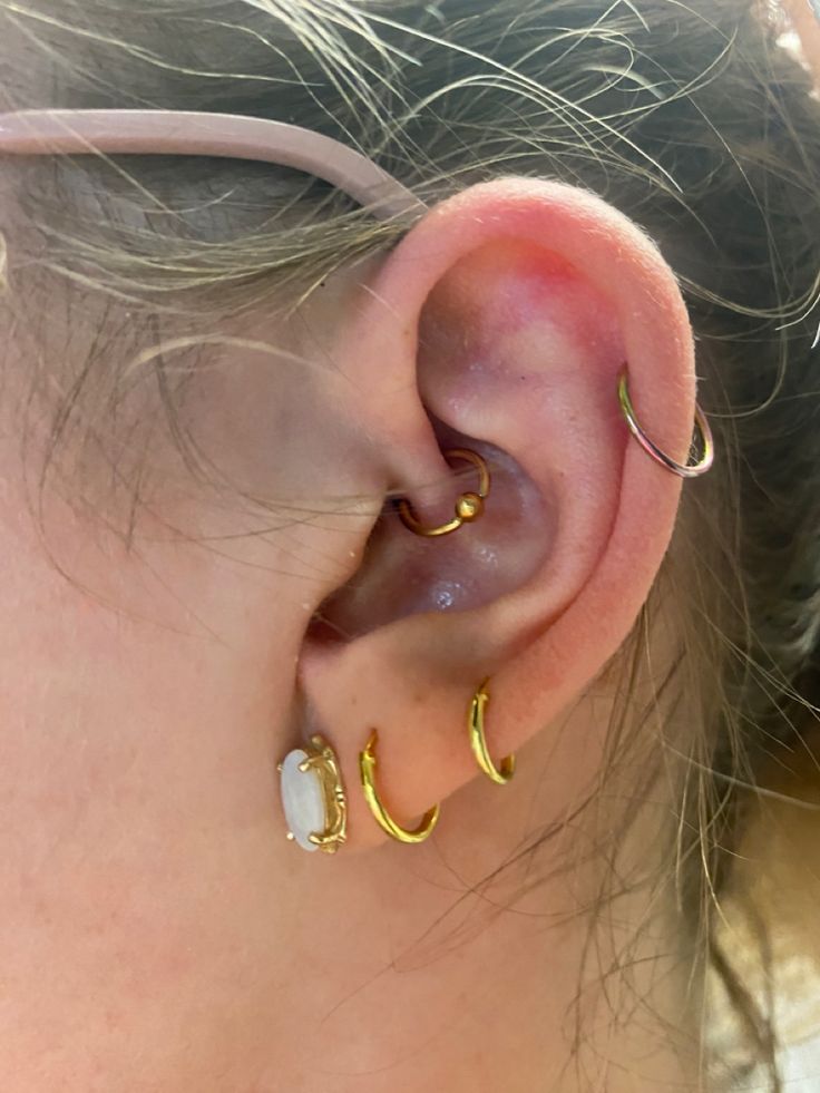 a close up of a person's ear with two gold hoops on it