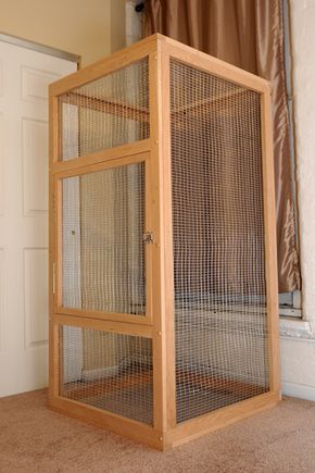 a large wooden cage sitting on top of a carpeted floor next to a door