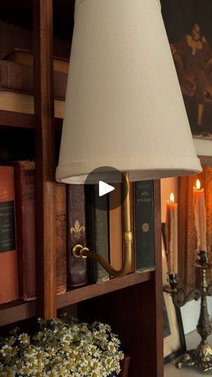 a lamp that is on top of a book shelf next to a vase with flowers