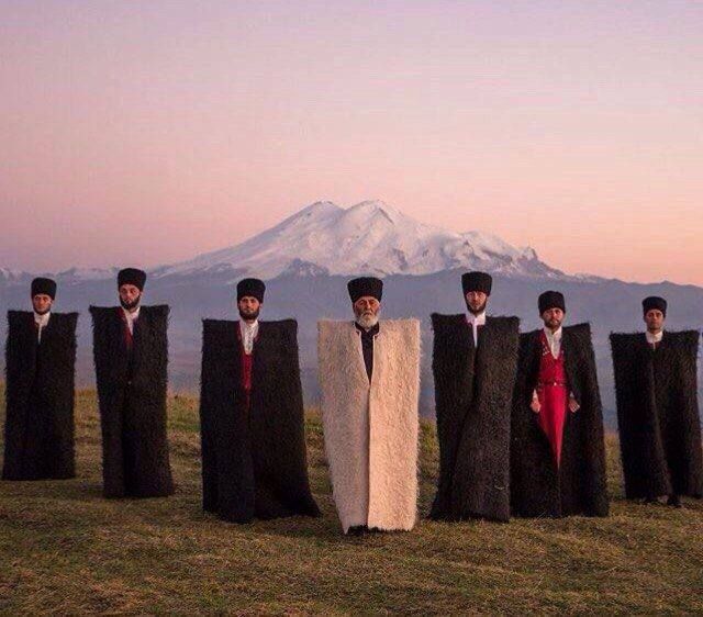 a group of people standing next to each other on top of a grass covered field