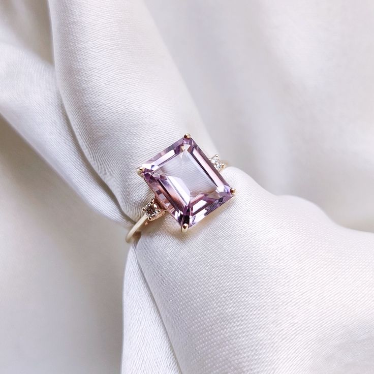 a ring with an amethorate stone on it sitting on top of a white cloth