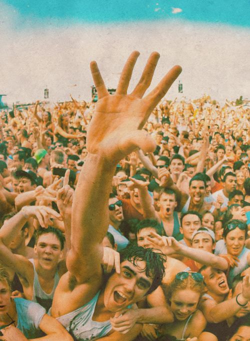 a large group of people standing in front of a crowd with their hands raised up