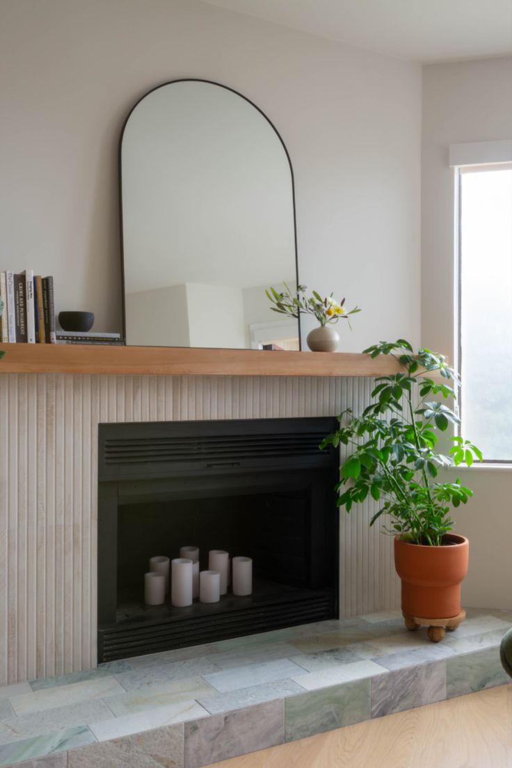 a living room with a fireplace, mirror and potted plant