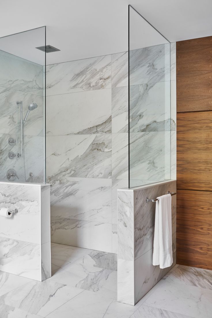 a bathroom with marble walls and flooring next to a walk - in shower stall