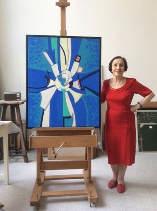 a woman standing in front of a painting and easel with her hands on her hips