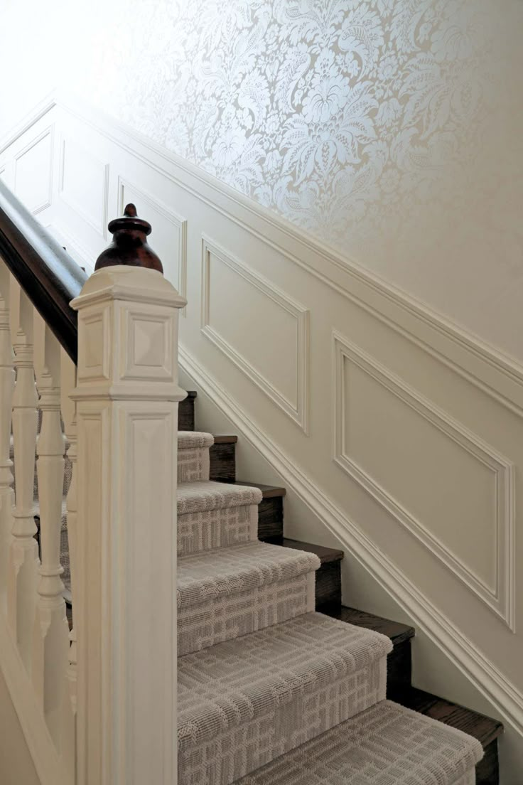 the stairs are lined with white carpet and decorative wallpaper