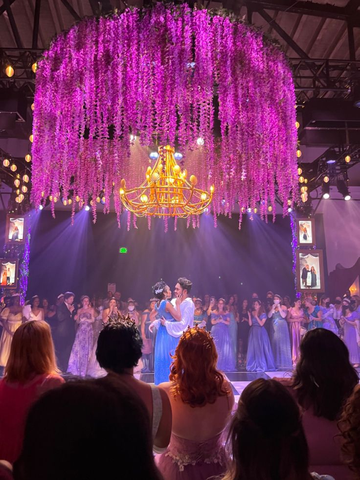 a group of people that are standing in front of a stage with chandeliers