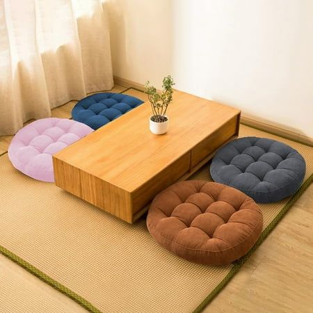 four different colored stools sitting on top of a rug next to a potted plant