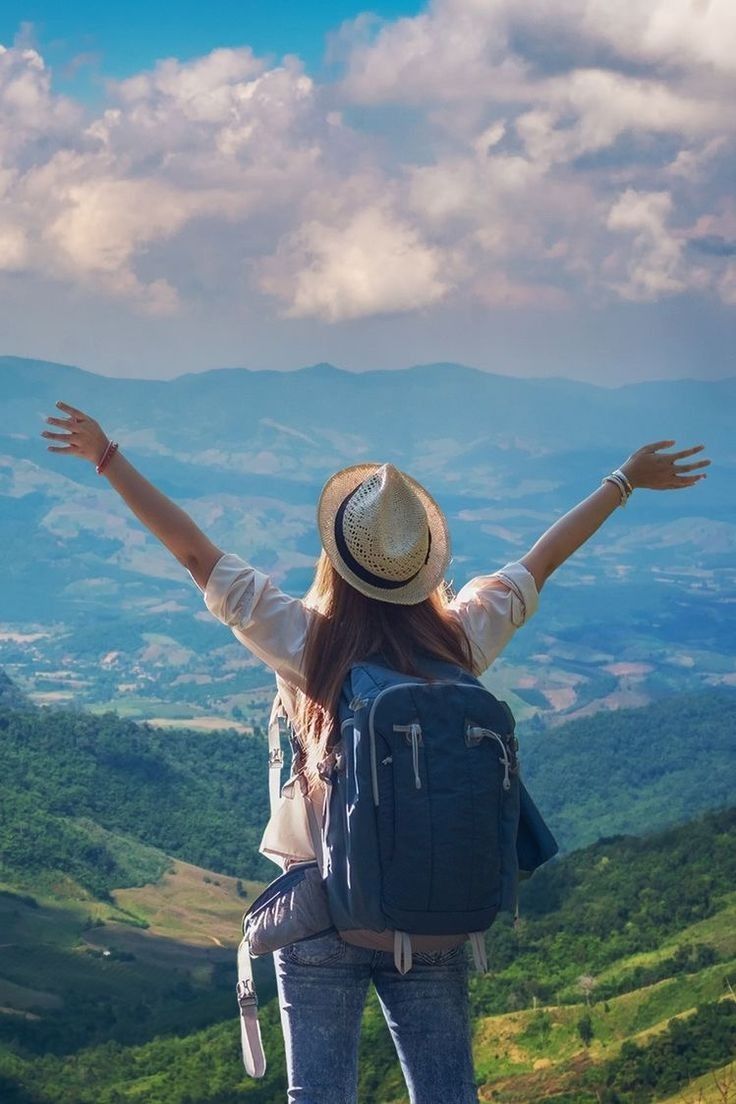 a woman standing on top of a mountain with her arms spread wide in the air