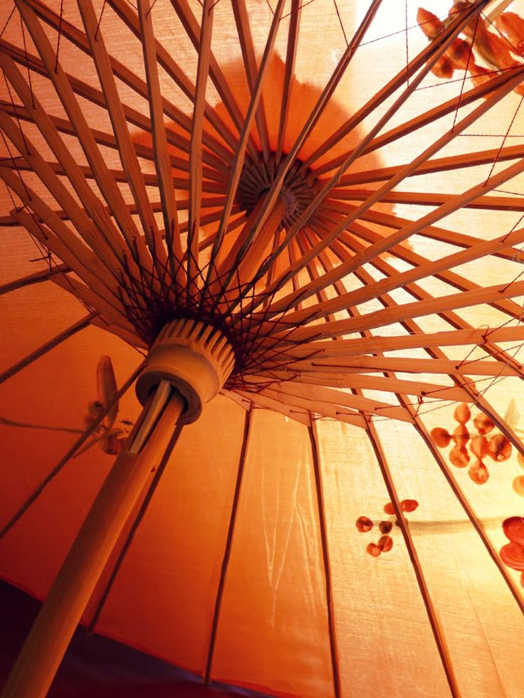 an orange umbrella is open and showing the light coming from it's center pole