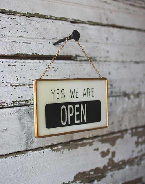 a sign hanging on the side of a wooden wall that says yes we are open